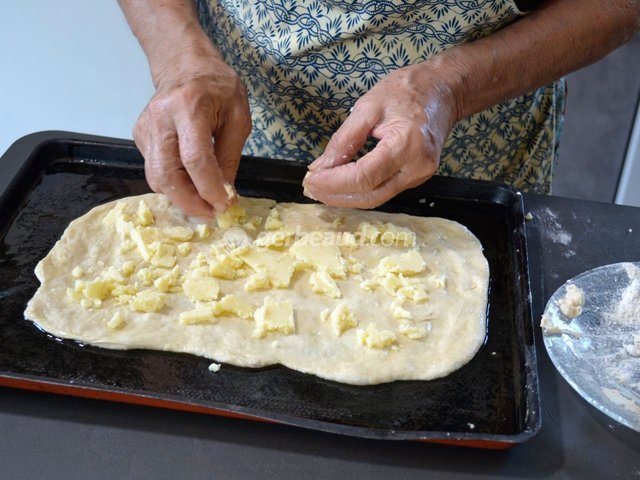 Garniture de la pâte étalée avec les morceaux de Cantal