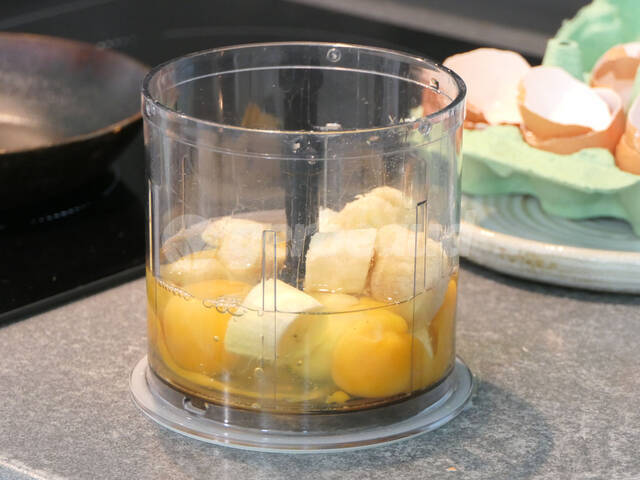 Oeufs et morceaux de banane dans le bol du mixer