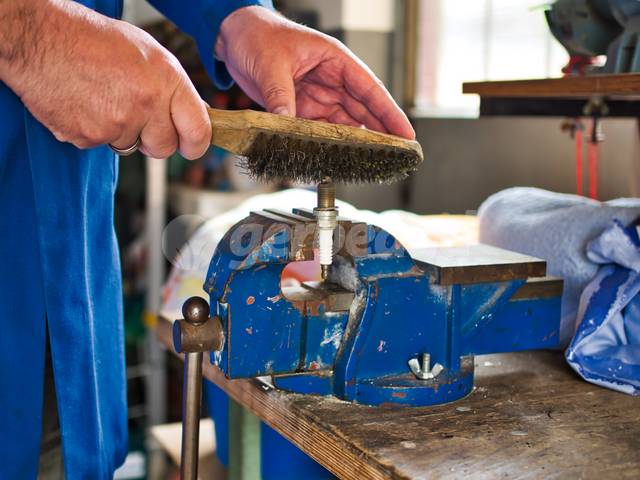 Nettoyage d'une bougie d'allumage à la brosse métallique
