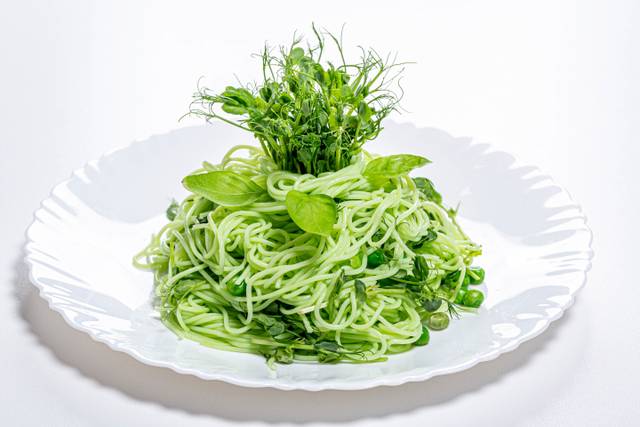Assiette de spaghettis avec jeunes pousses de pois et pois frais