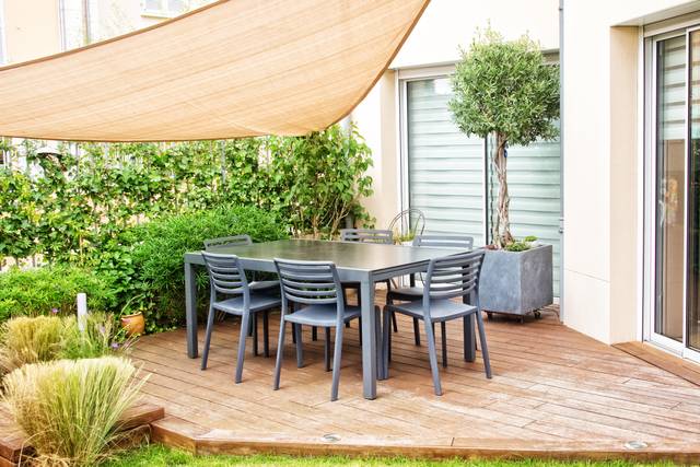 Coin repas d'une terrasse protégé par une voile d'ombrage