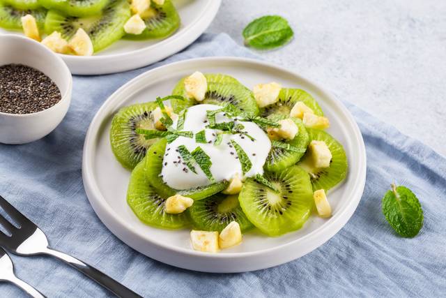 Salade de kiwi, avec morceaux de banane rôtie, feuilles de menthe et yaourt nature